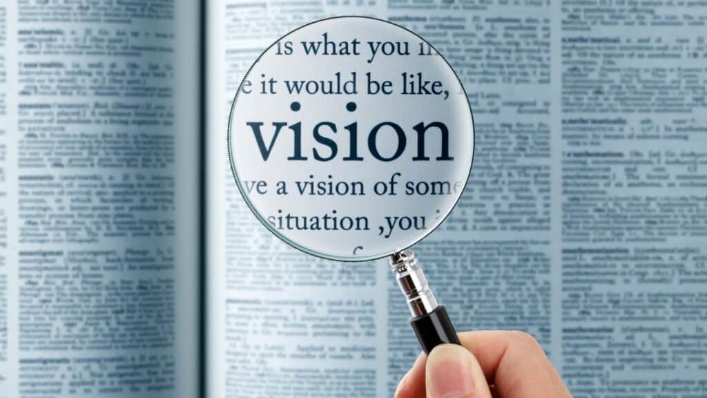 Magnifying glass over the word vision in a dictionary—symbolizing clarity, definition, and direction